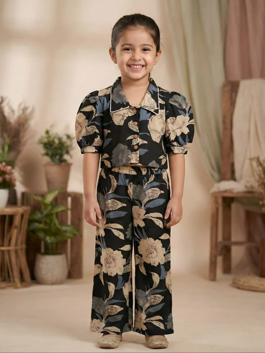Girl wearing black floral co-ord set with puff sleeve collared top and wide leg pants front view
