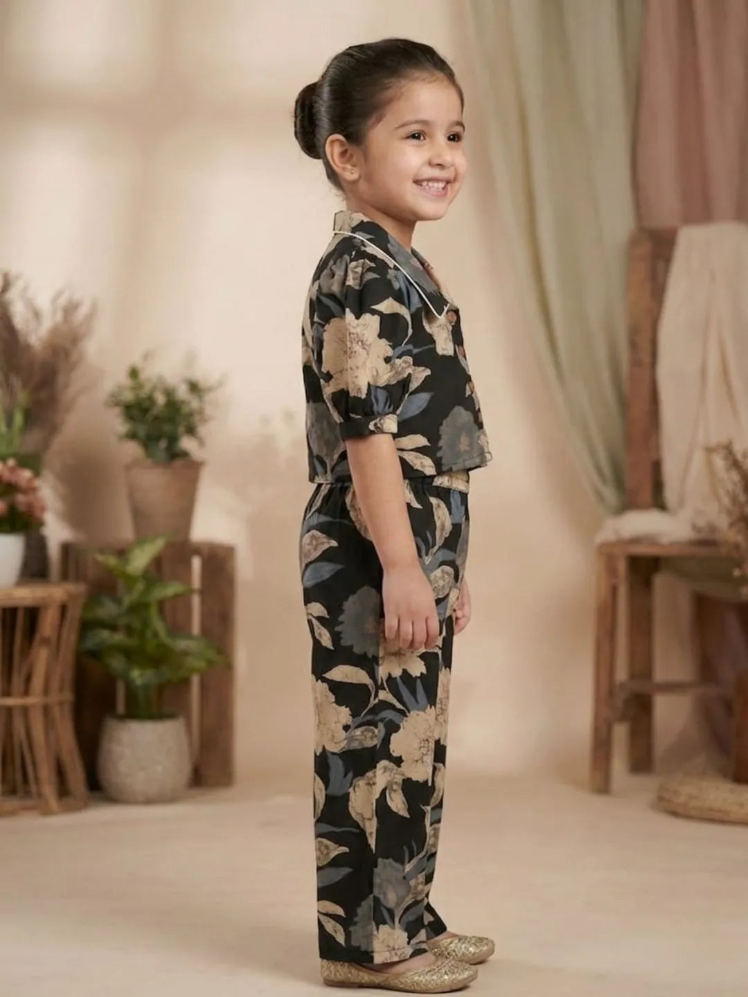 Side view of girls black floral co-ord set showing puff sleeve top and wide leg pants