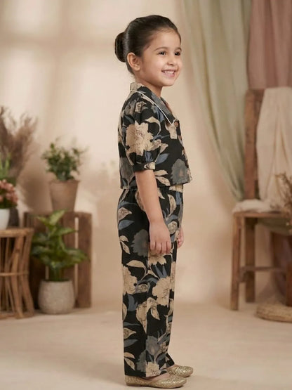Side view of girls black floral co-ord set showing puff sleeve top and wide leg pants