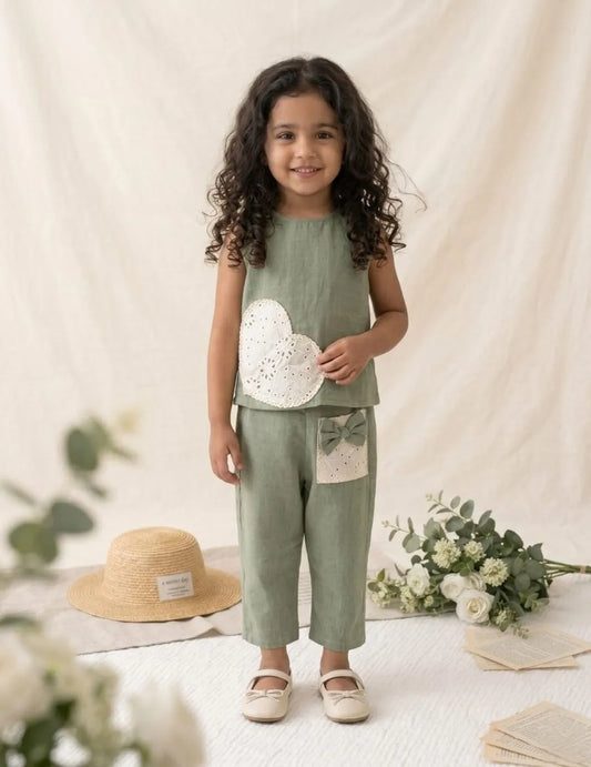 girl wearing green cotton co-ord set front view with lace heart and bow detail