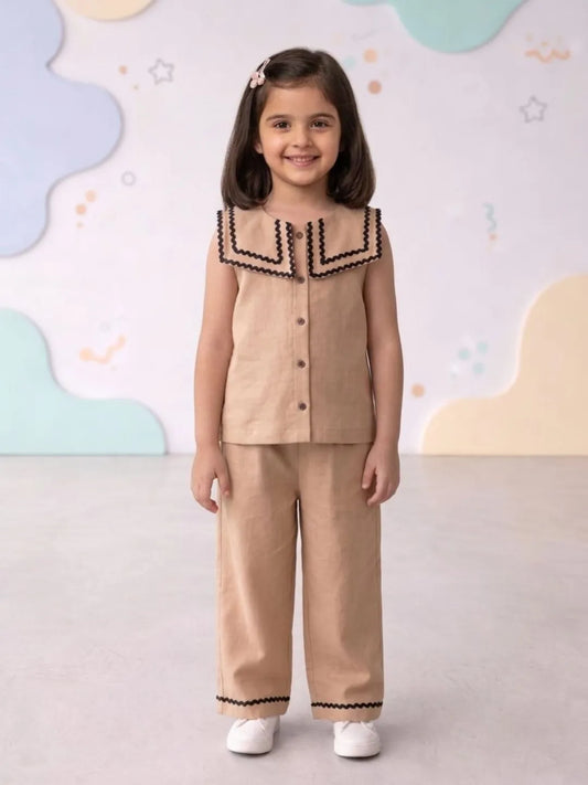 Young girl wearing a beige outfit with black trim against a colorful abstract background