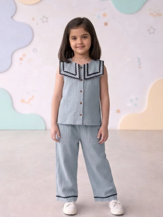 Young girl wearing a light blue outfit with a decorative top against a colorful background