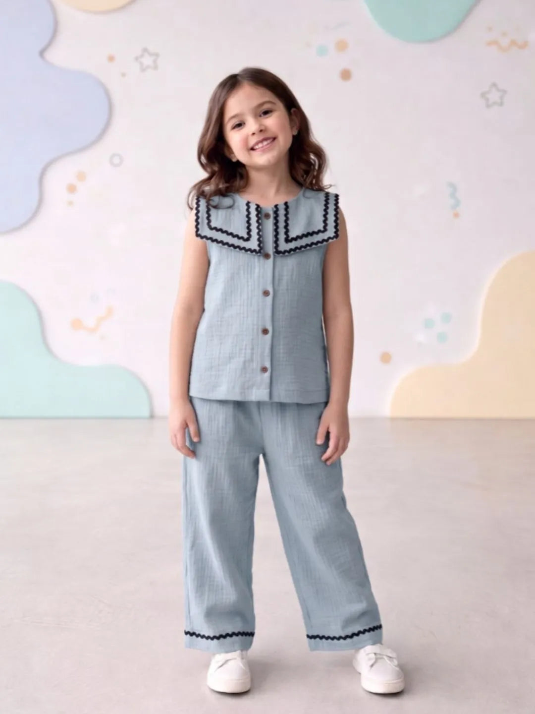 Young girl wearing a light blue outfit with decorative trim against a colorful abstract background