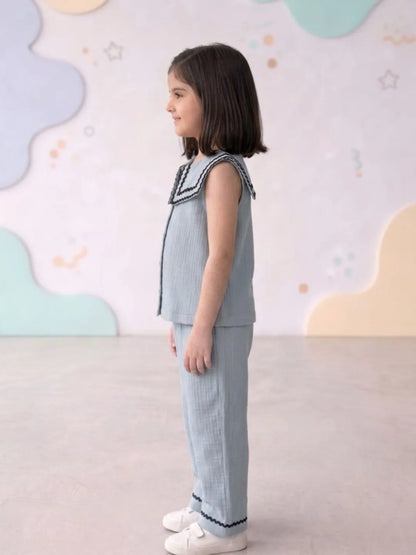 Young girl wearing a light blue outfit with decorative elements against a colorful background