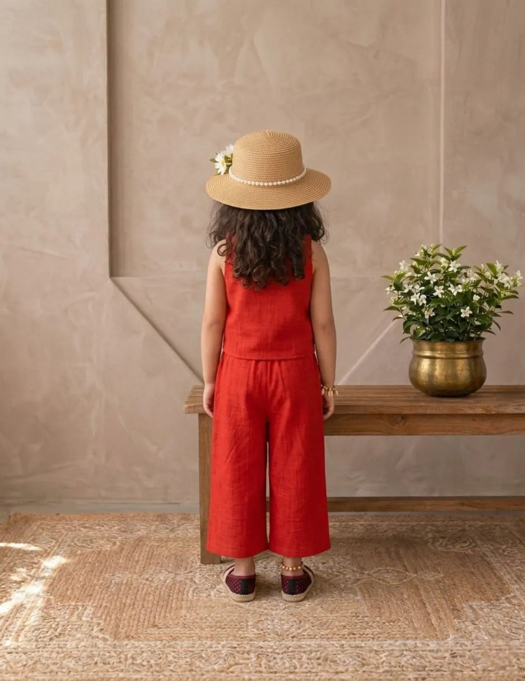 Lifestyle image of little girl in red cotton co-ord set in a minimal indoor setting
