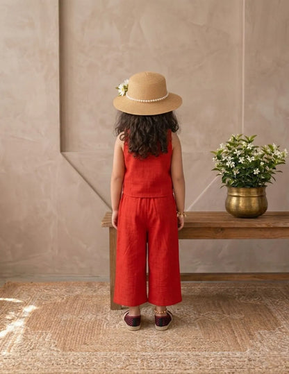 Lifestyle image of little girl in red cotton co-ord set in a minimal indoor setting