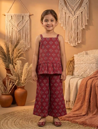 Girl wearing red printed co-ord set front angle view with sleeveless peplum top and wide leg pants