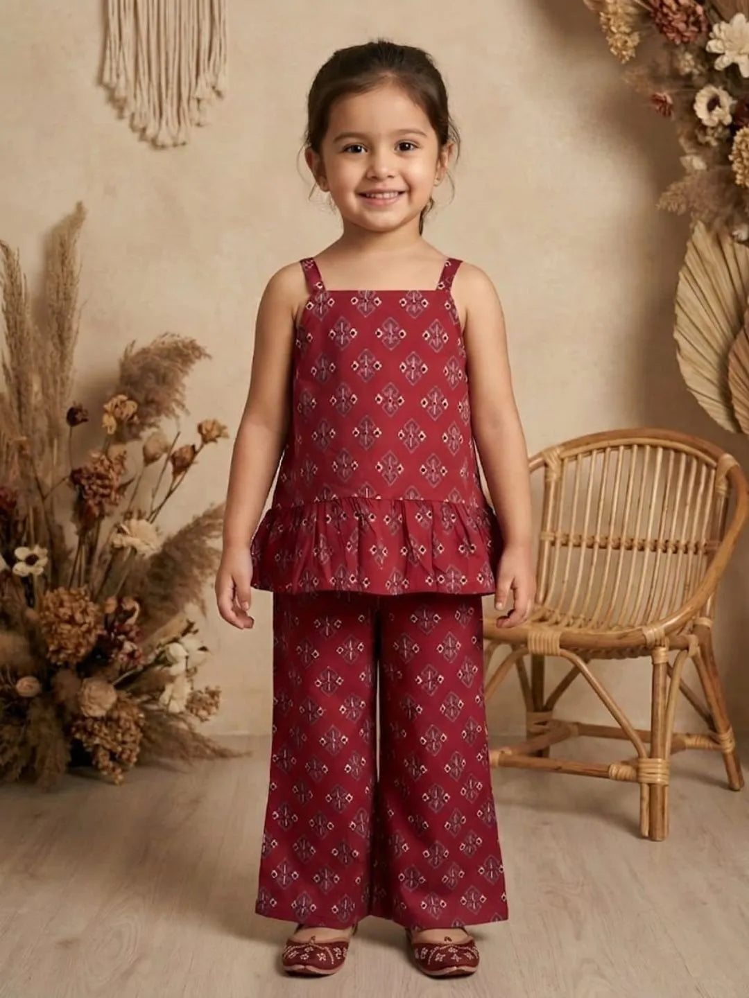 Girl wearing red printed co-ord set with sleeveless peplum top and wide leg pants front view