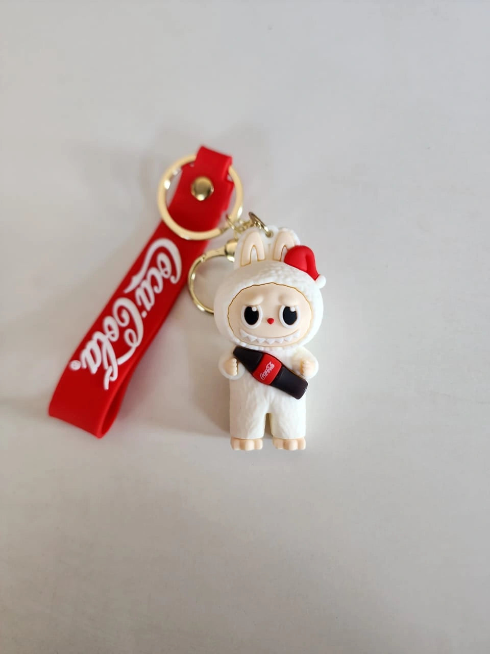 Keychain with a character holding a Coca-Cola bottle on a gray background