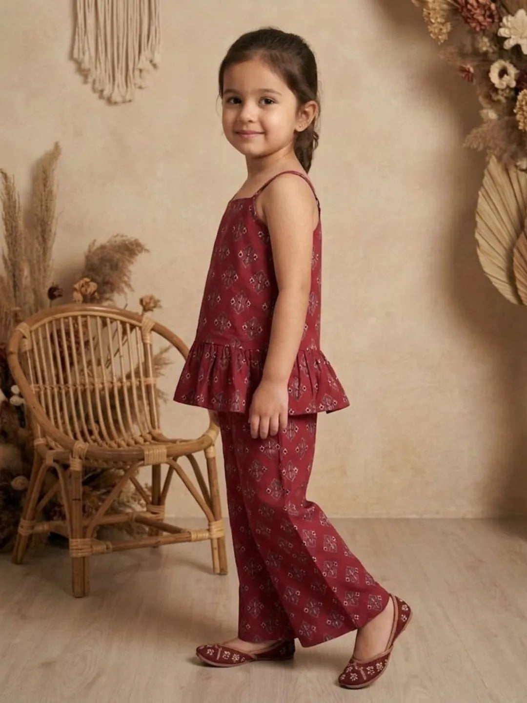 Side view of girls red printed co-ord set with sleeveless peplum top and wide leg pants